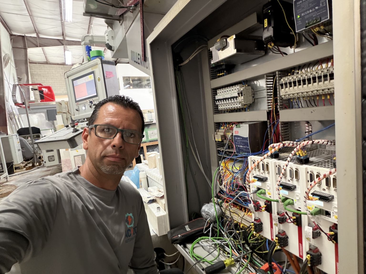 AC/DC Automation technician diagnosing an industrial control cabinet